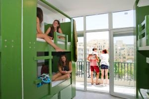a group of girls sitting on bunk beds in a building at Marco Polo Party Hostel in St. Julianʼs