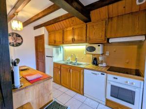 eine Küche mit Holzschränken und weißen Geräten in der Unterkunft Chalet familial dans le Parc des Vosges, wifi et animaux acceptés - FR-1-589-840 in Le Ménil + 27 Fotos
