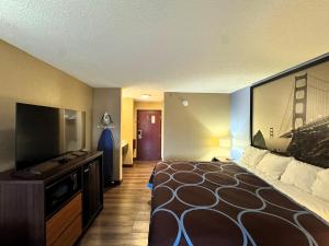a hotel room with a bed and a flat screen tv at Super 8 by Wyndham Booneville in Booneville