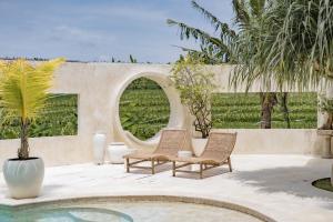 a patio with two chairs and a circular mirror at Rumah Simba in Munggu