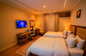 a hotel room with two beds and a desk and a television at Nora light clouds inn in Cairo