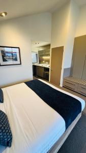 a large white bed in a room with a kitchen at Garden Court Suites & Apartments in Queenstown