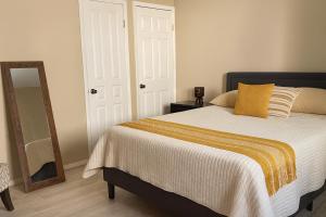 a bedroom with a bed with a yellow blanket and a mirror at Stellarium Hotel in Ensenada
