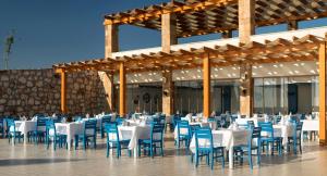 a dining hall with white tables and blue chairs at Aquasis De Luxe Resort & SPA - Ultra All Inclusive in Didim