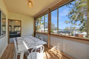 a dining room with a table and chairs and windows at Greville on the Bay in Sanctuary Point +4 photos
