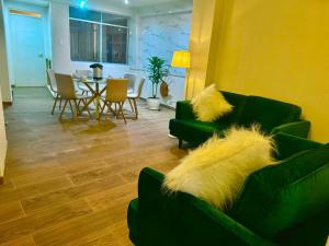 ein Wohnzimmer mit grünen Sofas sowie einem Tisch und Stühlen in der Unterkunft Departamento de Ensueño in Huaraz