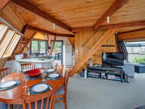 a dining room with a table and chairs and a kitchen at The Sorting Hat - Pauanui Holiday Home in Pauanui