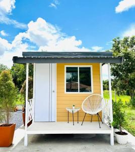 a tiny house with a porch and a chair at RT House Resort in Ban Phawon