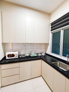 Una cocina con gabinetes blancos, un fregadero y un microondas. en Pink DO HOMESTAY, en Kajang 6 fotos más
