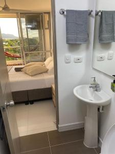 a bathroom with a sink and a bed with a window at Apartamento Ricaurte 90 m2, 3 habitac, 6 personas, Peñazul La Morada LuisFeryClarita in Ricaurte