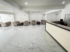 een man zit aan een balie in een kamer met marmeren vloeren bij Hotel Crown Plaza in Prayagraj