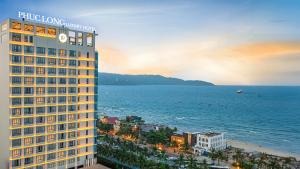 岘港PHUC LONG LUXURY Danang的一座高大的建筑,在海边有一个钟