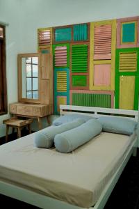 a bed in a room with a wall with colorful shutters at Desa Huis Yogyakarta in Gandok