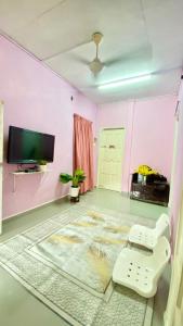 a living room with pink walls and a tv at Homestay Bajet Rantau Panjang  +4 photos