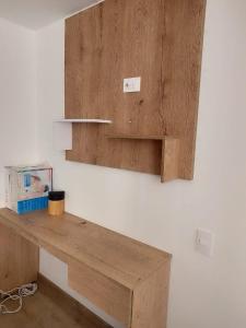 a wooden desk on a white wall with a shelf at Modern studio in a tourist and university area in Bogotá