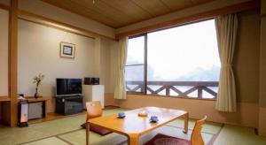 a living room with a table and a large window at Takato Sakura Hotel in Ina
