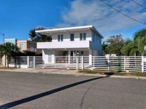 een wit huis met een hek ervoor bij White House Paradises in Cabo Rojo