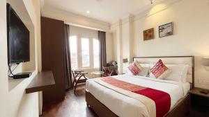 a hotel room with a bed and a flat screen tv at New Hotel Broadway in Varanasi