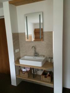 La salle de bains est pourvue d'un lavabo blanc et d'un miroir. dans l'établissement Gästehaus Schneeberger, à Matrei in Osttirol