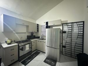 a kitchen with stainless steel appliances and white cabinets at Zae's Retreat 2 bed 1 Bath in Portmore Jamaica in Newlands