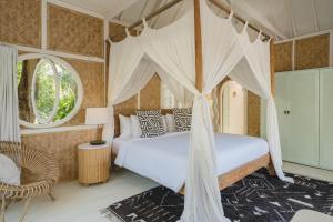 a bedroom with a canopy bed and a chair at Bodhi Bingin in Uluwatu +114 photos