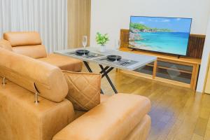 Una sala de estar con un televisor y dos sillas y una mesa. en 糸島リトリートヴィラ芥屋, en Itoshima