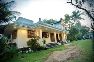 a small white house with a green yard at Estella Marari Beach Villa in Mararikulam