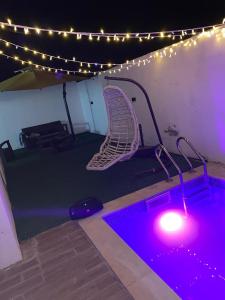 une piscine avec une chaise dans une pièce avec des lumières dans l'établissement Coquette villa, à Hammamet Sud