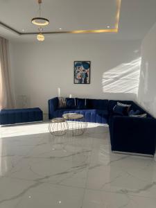 un salon avec un canapé bleu et deux tables dans l'établissement Coquette villa, à Hammamet Sud 7 autres photos