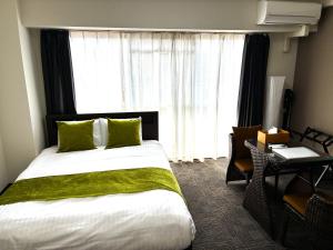 a hotel room with a bed and a desk and a window at エレガンス京町 -岡山市内中心部 路面電車の駅まで徒歩5分 のんびりステイ in Okayama