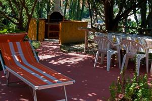 a bench and two chairs and a table and a grill at Aparthotel Villa Marinù in Ischia