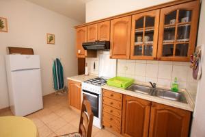 a kitchen with wooden cabinets and a white refrigerator at Apartments Miro with Sea view - near Beach in Sumartin