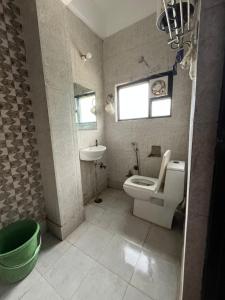 a bathroom with a toilet and a sink and a window at Rockwood Inn in Faridabad