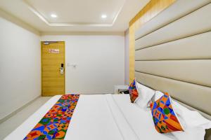 a bedroom with a bed with a wooden headboard at FabHotel Prime Veeraj Suites- Nr Skyview10, Lumbini Avenue, Gachibowli in Hyderabad
