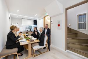 eine Gruppe von Menschen, die an einem Tisch in einem Haus sitzen in der Unterkunft STAY ARI Higashishinjuku in Tokio