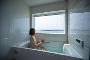 大山町にあるDAISEN UMIHOTARU Entire houseの浴槽に座って窓の外を眺める女性 +23枚の写真