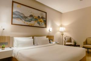 a bedroom with a large white bed and a chair at Udman Hotel Gurugram in Gurgaon +56 photos