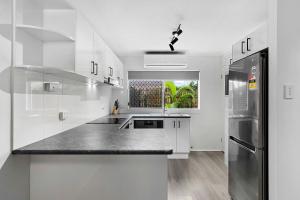 una cucina con mobili bianchi e un piano di lavoro nero di Coast Apartments 2 Bedroom Getaway a Torquay