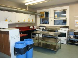 a kitchen with white cabinets and a table in it at Surf 'N' Snow Backpackers Across Sky Tower in Auckland
