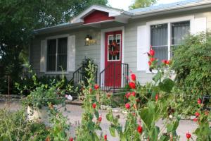 a white house with a red door and flowers at Onion Creek Cottage in Austin