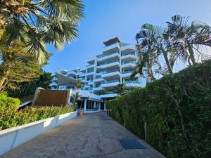 a large white building with palm trees and a sidewalk at 2 Bedrooms Apartment pool access in Ban Lum Fuang