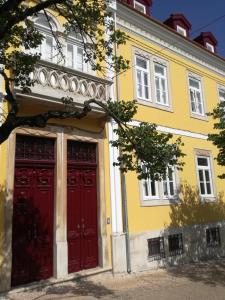 a yellow and red building with two red doors at Ah33 - Estúdios in Coimbra