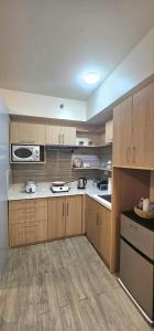 a large kitchen with wooden cabinets and a microwave at Sweet Escape 311 at Amaia in Bacolod