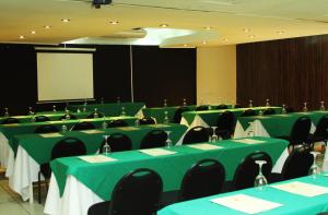 a conference room with green tables and chairs and a screen at Hotel Estrella in Managua