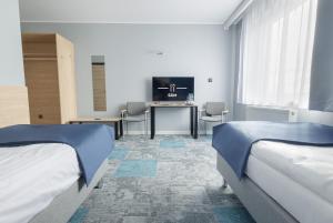 a room with two beds and a desk and a television at Platynowa in Września