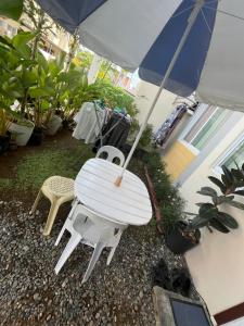 une table blanche, deux chaises et un parasol dans l'établissement The Airport Guest House by Casa Brisa, à Davao