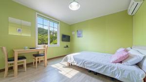 a bedroom with a bed and a desk and a window at Gapyeong Four Season Pension in Gapyeong