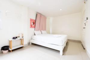 een witte slaapkamer met een bed en een tafel bij Oh My Nap- Sukhumvit Soi 3 BTS Nana in Bangkok