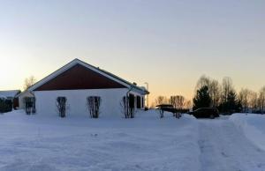 a barn in a snow covered field with a car at Vasko Luxurious Suites, Firefox in Rovaniemi