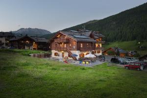 a large wooden house in a field of grass at Hotel San Giovanni in Livigno